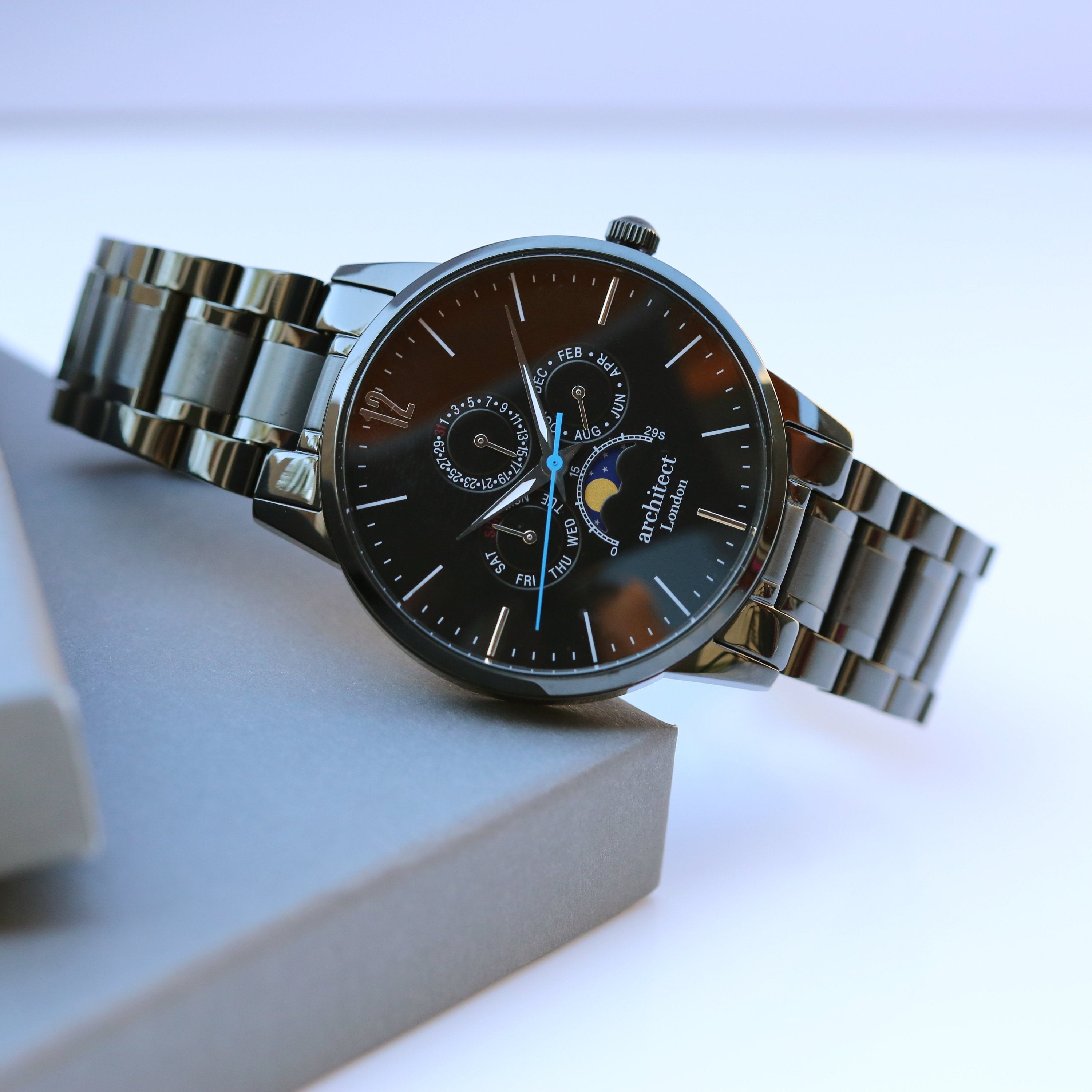 Silver watch with a black face on a light gray surface