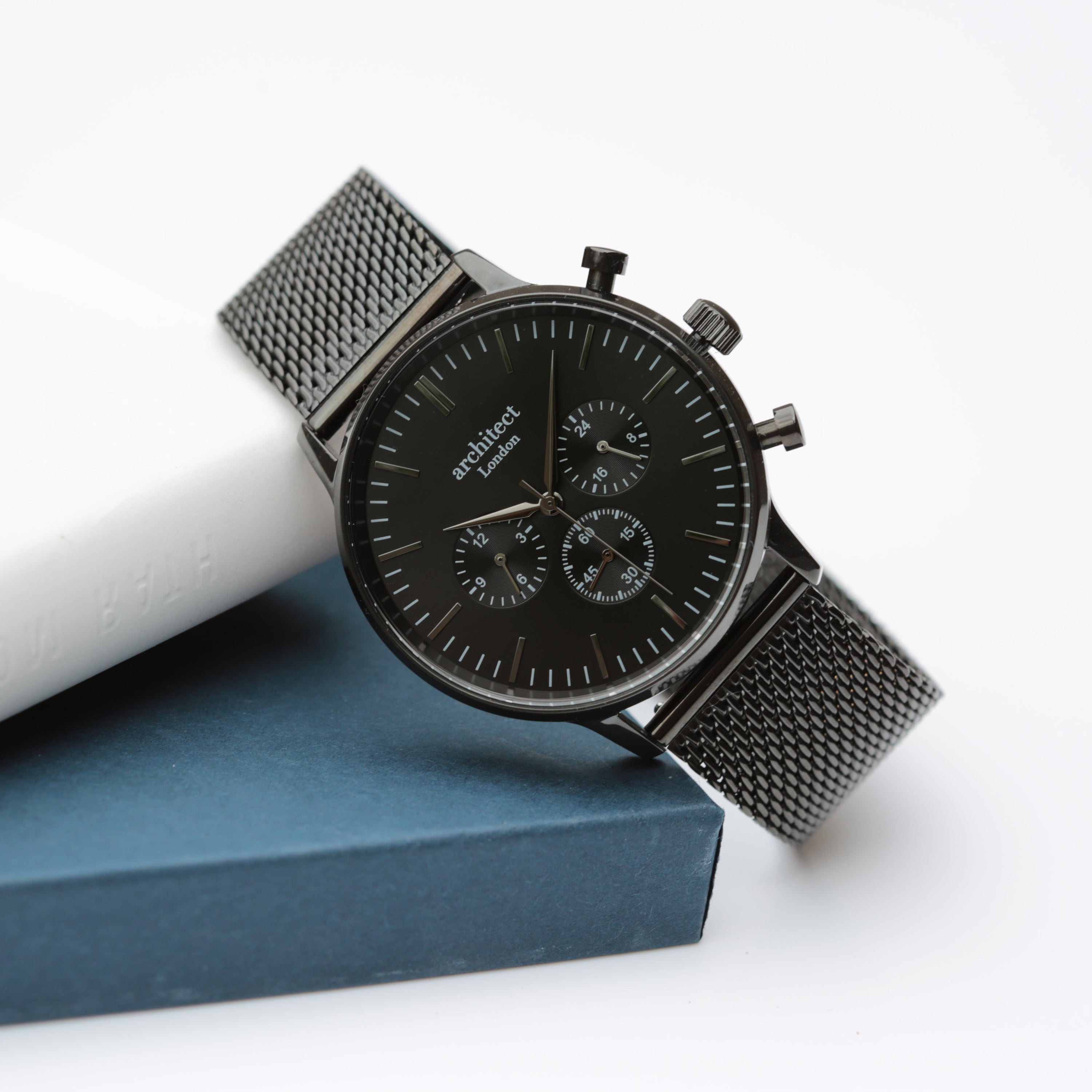 Black watch with mesh band on a white surface