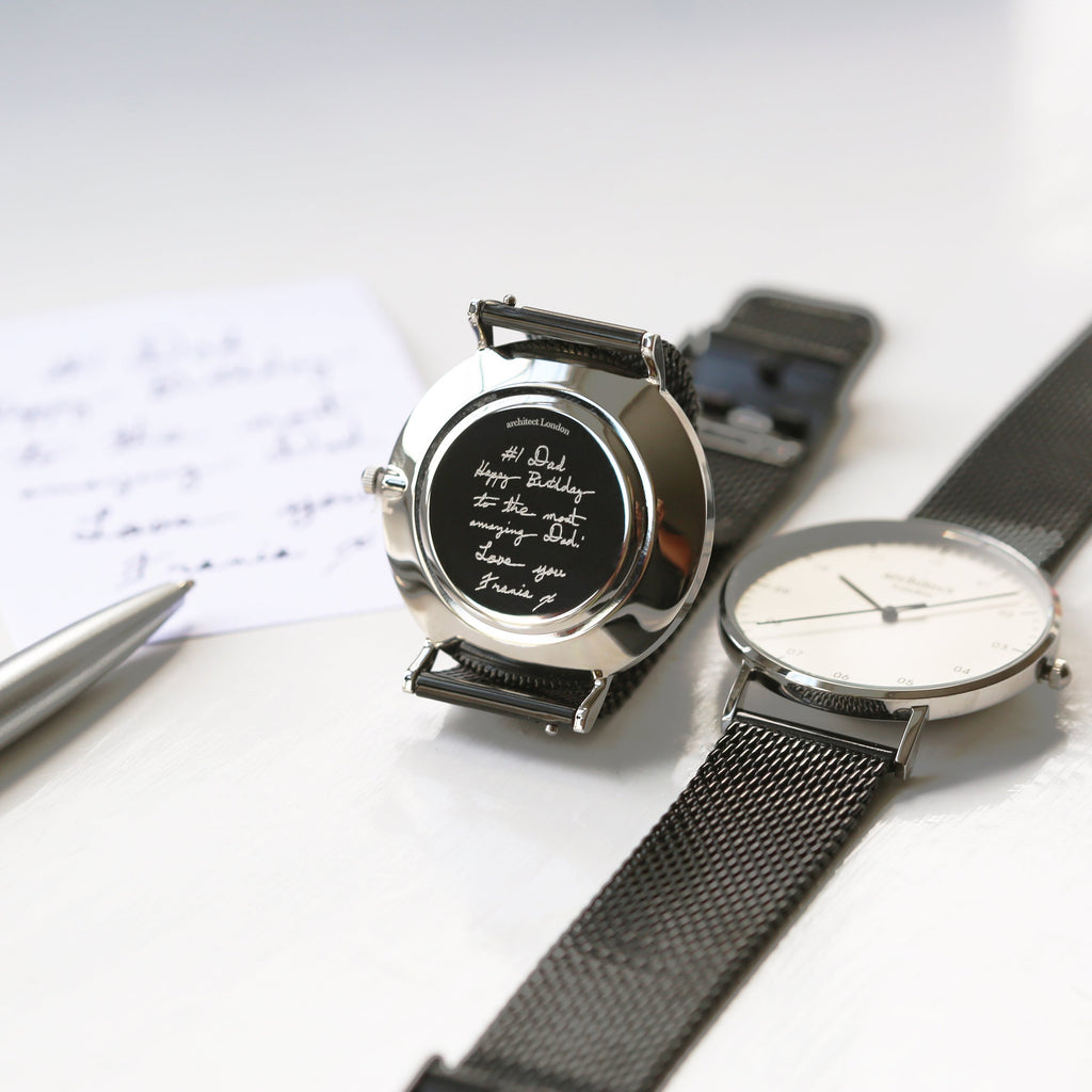 Two watches with black and silver straps on a white surface.

