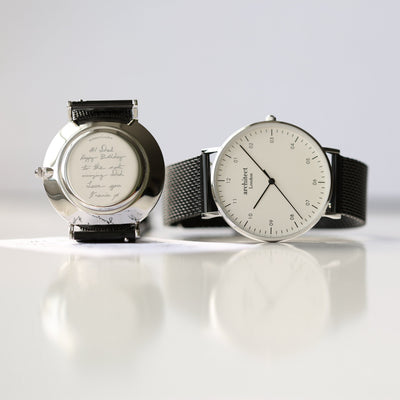 Two watches on a reflective surface with a light gray background

