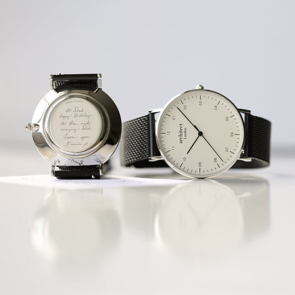Two watches on a reflective surface with a light gray background

