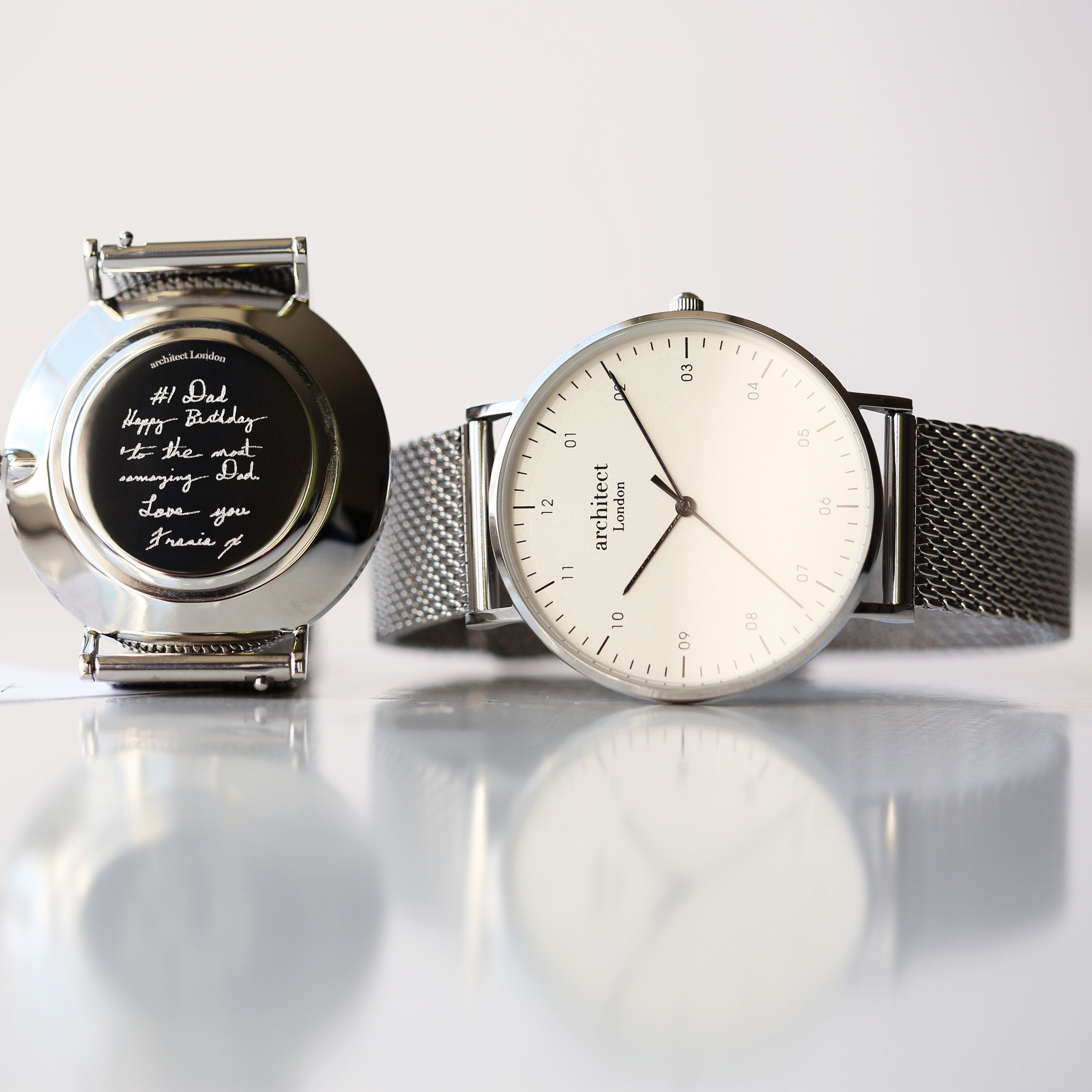 Two watches on a reflective surface with a light gray background