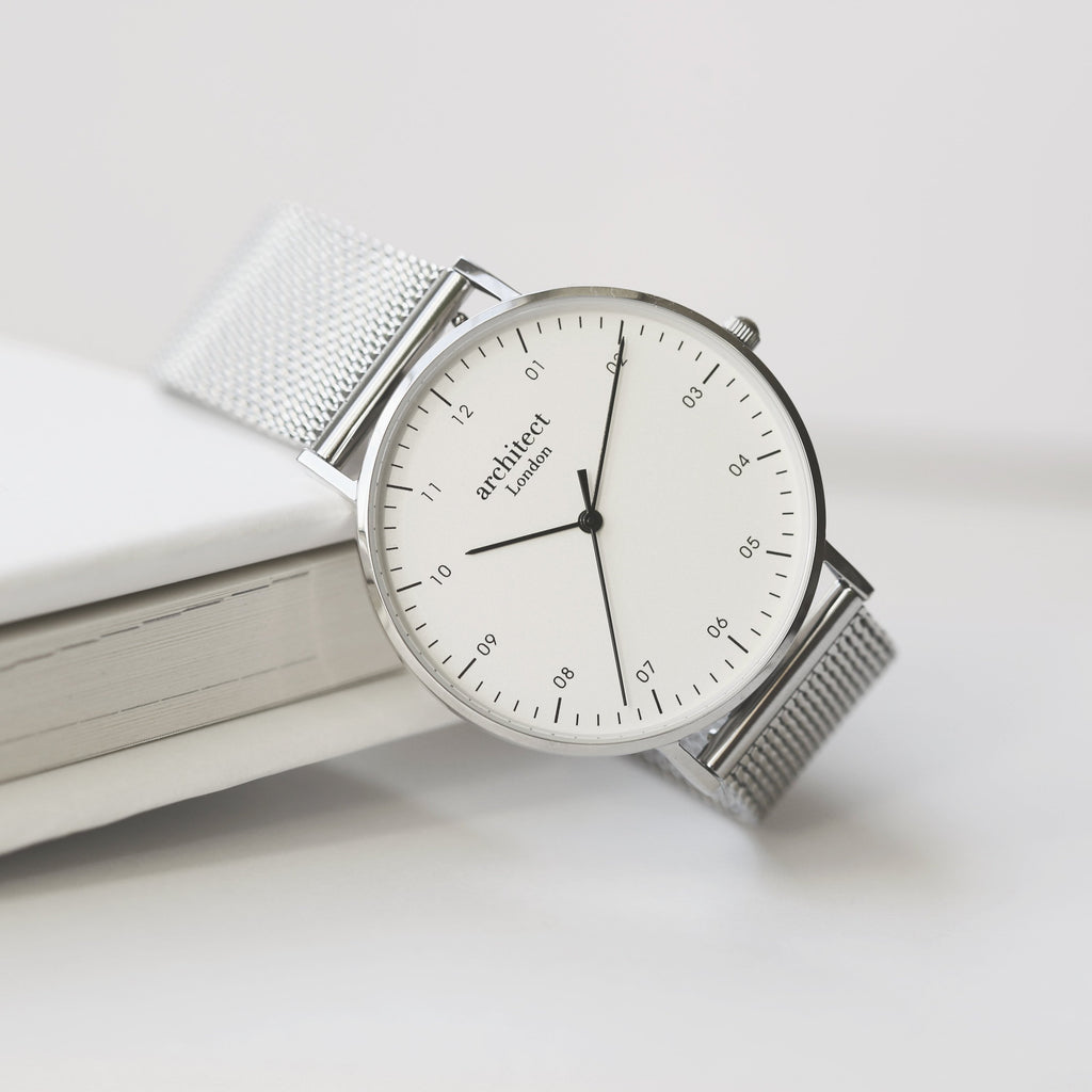 Silver watch with a white face on a light surface