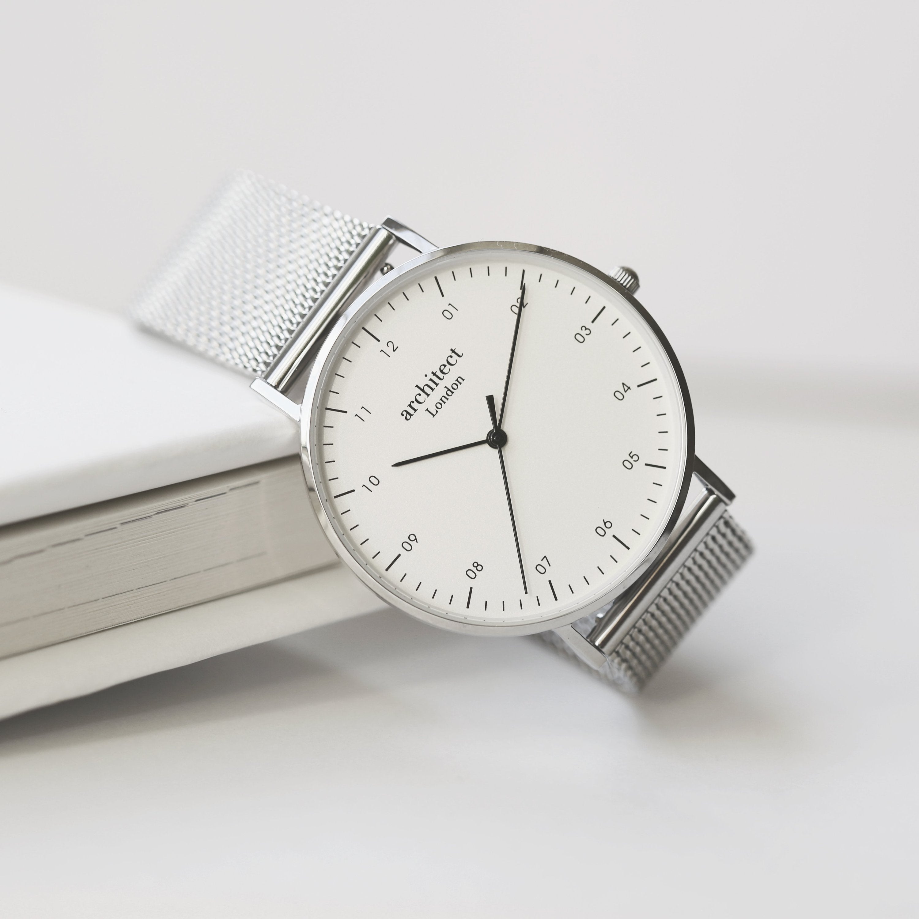 Silver watch with a white face on a light surface