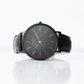 Black wristwatch with a reflective surface on a white background