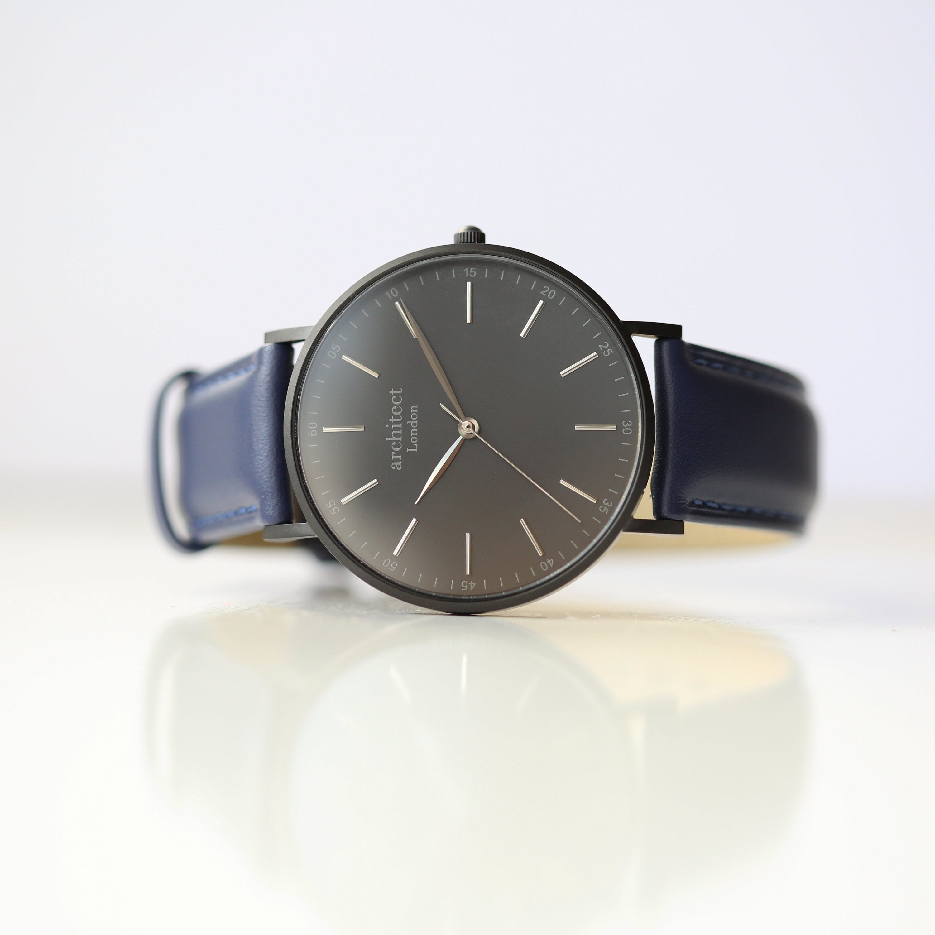 Wristwatch with dark blue leather strap on a reflective surface