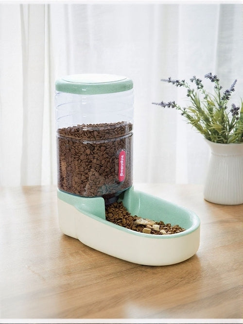 Pet food dispenser with food on a wooden floor next to a plant