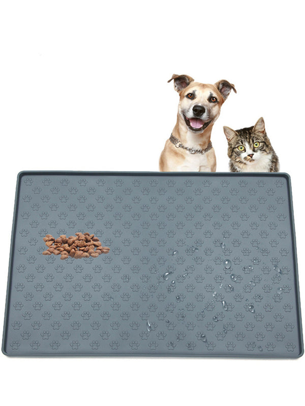 Dog and cat sitting behind a large gray pet mat with food on a white background

